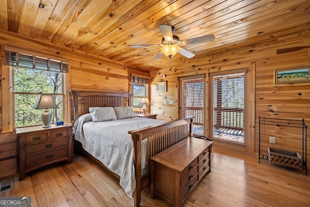 bedroom with access to exterior, wooden walls, wood ceiling, and light wood-style floors