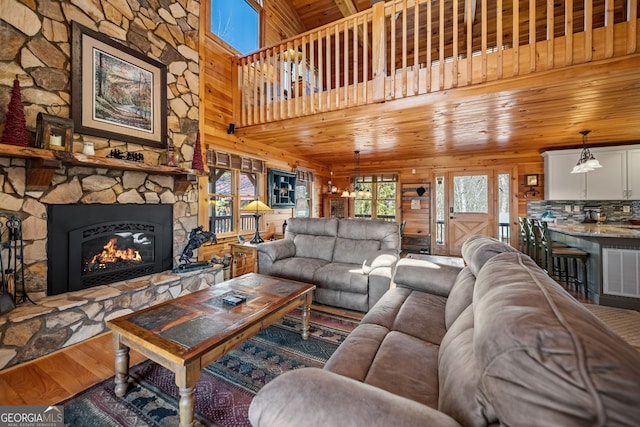 living area featuring a fireplace, visible vents, wooden walls, wood finished floors, and wooden ceiling