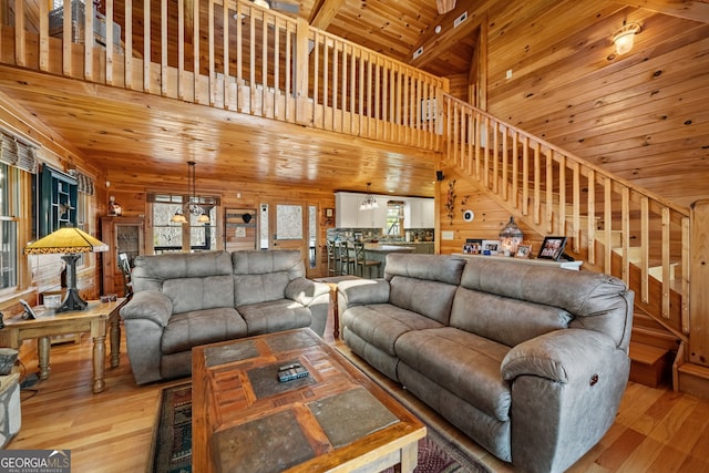 living room featuring wooden ceiling, stairs, light wood finished floors, and wood walls