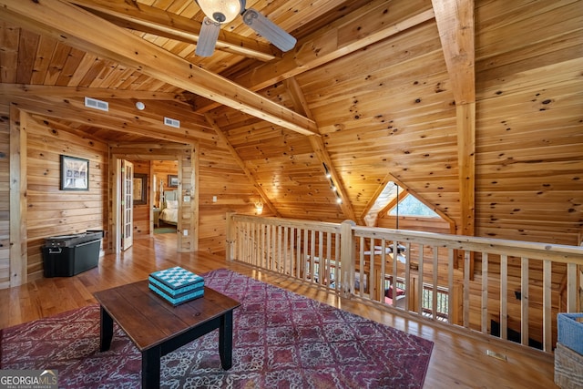 living room with lofted ceiling with beams, wooden ceiling, wood walls, wood finished floors, and visible vents