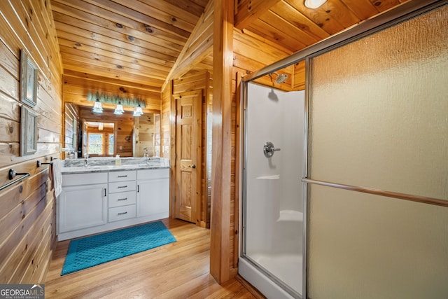 bathroom with double vanity, wooden walls, wood ceiling, wood finished floors, and a shower stall