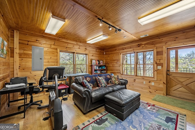 living room with light wood-style floors, wood ceiling, electric panel, and wood walls