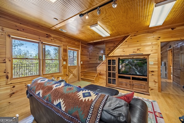 bedroom with light wood-type flooring, track lighting, wooden ceiling, and wooden walls