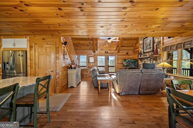 living room with wood walls, wooden ceiling, a fireplace, and a healthy amount of sunlight