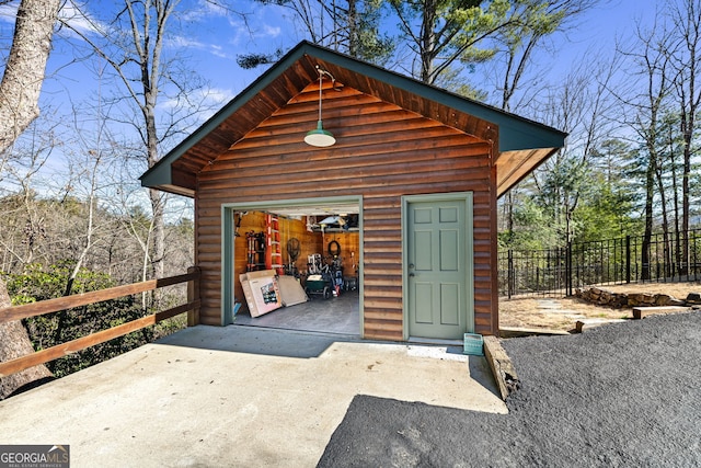 view of outdoor structure with an outbuilding, concrete driveway, and fence