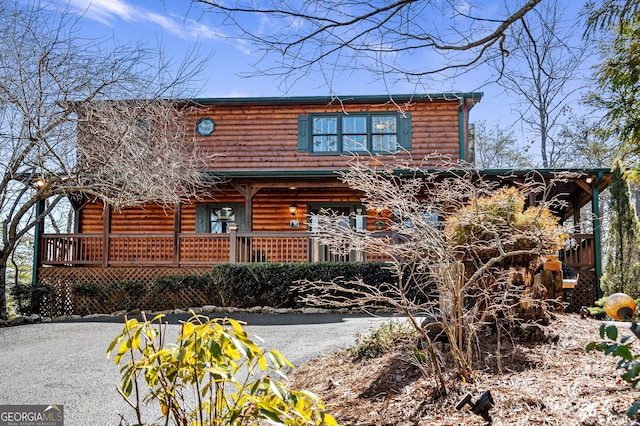 log cabin featuring covered porch and log veneer siding