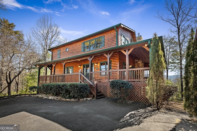 view of front facade with a porch and faux log siding