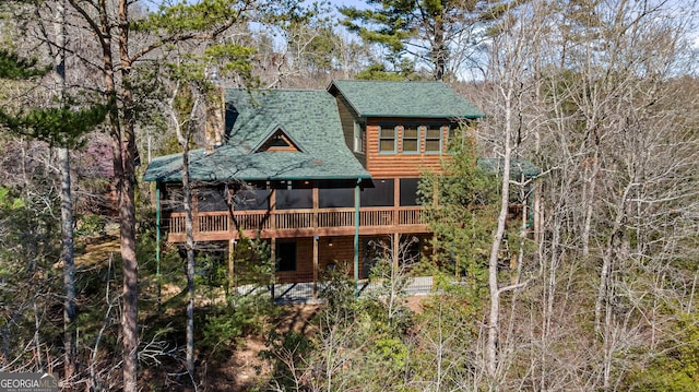 rear view of house featuring a deck, roof with shingles, and log veneer siding