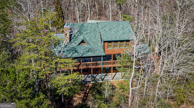 exterior space featuring a deck, roof with shingles, a patio area, and log veneer siding