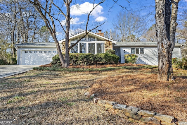 mid-century modern home featuring driveway, a garage, and a chimney