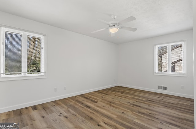 spare room with a ceiling fan, baseboards, visible vents, and wood finished floors