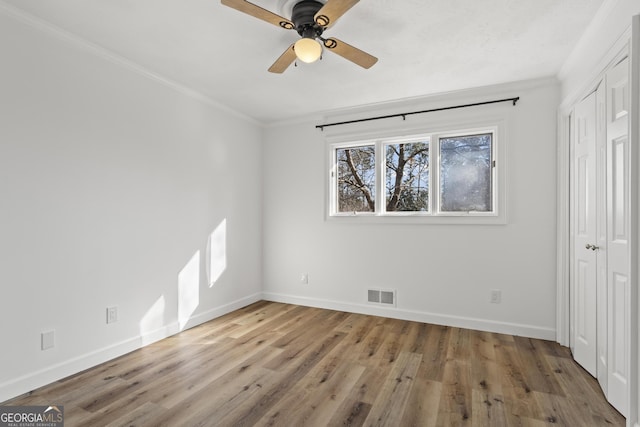 unfurnished bedroom featuring ornamental molding, wood finished floors, visible vents, and baseboards