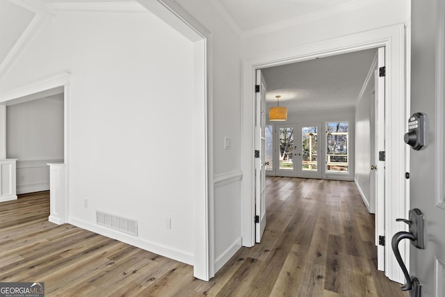 hall featuring french doors, visible vents, crown molding, and wood finished floors