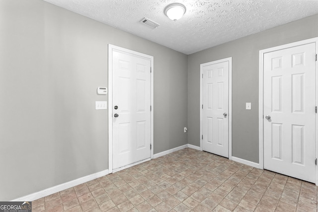 entrance foyer with visible vents, a textured ceiling, and baseboards