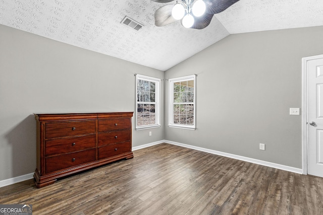 unfurnished bedroom with wood finished floors, visible vents, baseboards, vaulted ceiling, and a textured ceiling