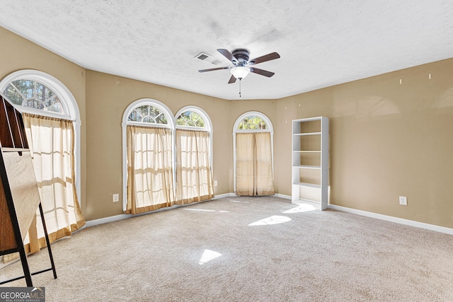 carpeted spare room with visible vents, a textured ceiling, and baseboards