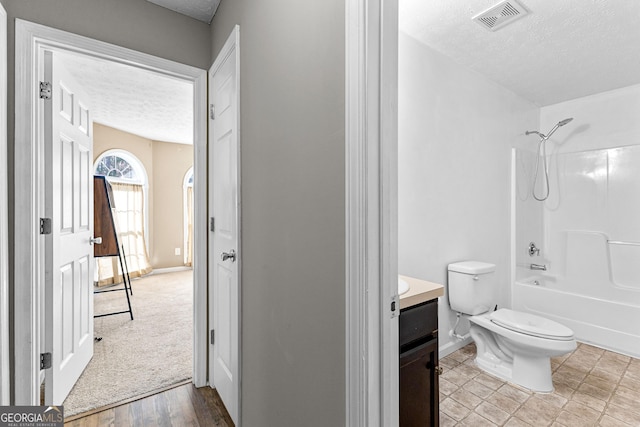 bathroom featuring visible vents, a textured ceiling, vanity, and toilet