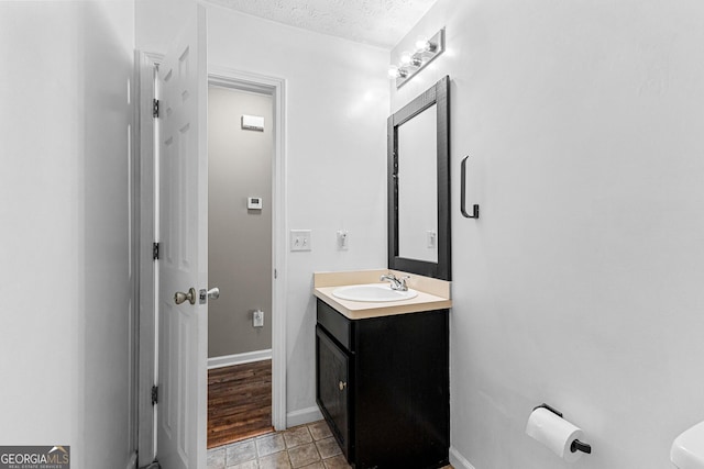 bathroom featuring baseboards, a textured ceiling, and vanity