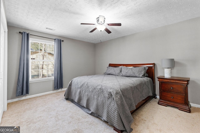 bedroom featuring visible vents, a textured ceiling, carpet floors, baseboards, and ceiling fan