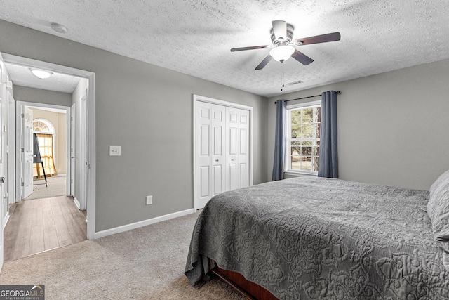 bedroom with a textured ceiling, a closet, carpet, baseboards, and ceiling fan