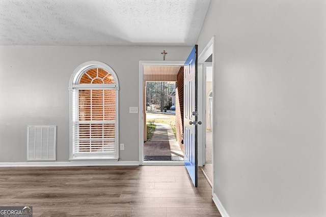 entrance foyer with visible vents, a textured ceiling, baseboards, and wood finished floors