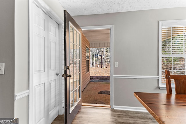 entryway with french doors, baseboards, a textured ceiling, and wood finished floors