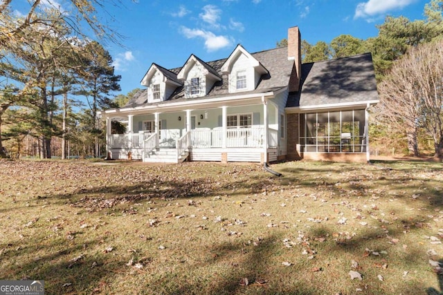 cape cod house featuring covered porch, a chimney, a front yard, and a sunroom