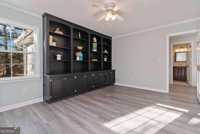 empty room featuring light wood-type flooring, baseboards, and crown molding