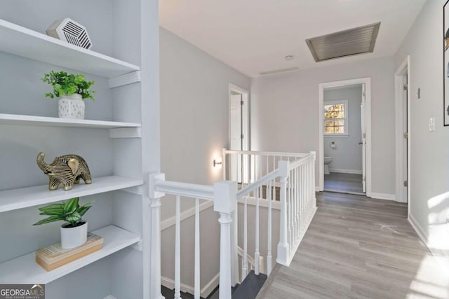 corridor with light wood finished floors, baseboards, and an upstairs landing