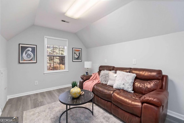 living room featuring lofted ceiling, wood finished floors, visible vents, and baseboards