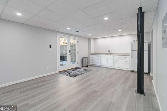 below grade area with recessed lighting, light wood-style flooring, freestanding refrigerator, a sink, and baseboards