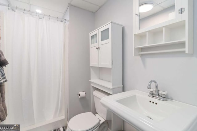 full bathroom featuring a paneled ceiling, a shower with shower curtain, a sink, and toilet