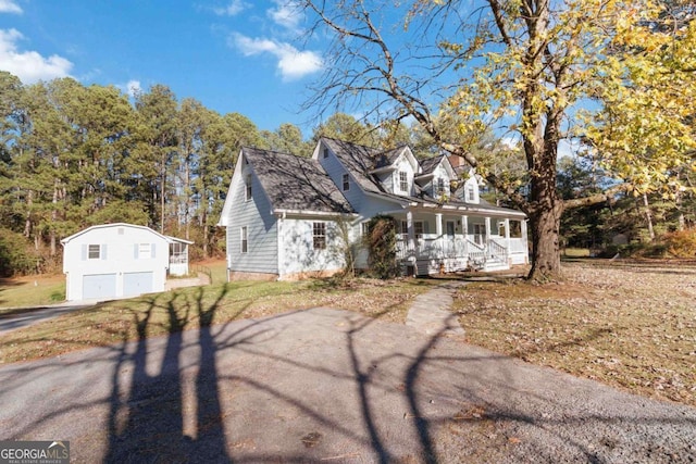 cape cod home featuring a garage, covered porch, and a front yard