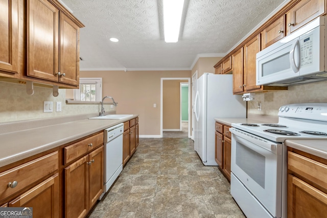 kitchen with white appliances, light countertops, a sink, and brown cabinetry