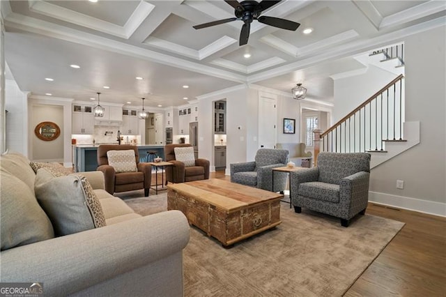 living area with light wood-style flooring, stairway, coffered ceiling, and crown molding