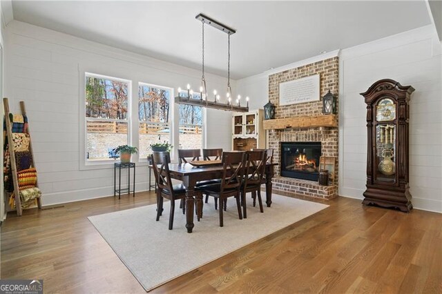 dining area featuring a fireplace, wood finished floors, and a notable chandelier