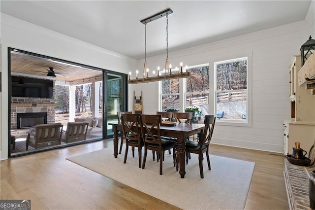 6326 Point Twenty Two, Gainesville, GA 30506 - dining room with light wood-type flooring, a brick fireplace, ornamental molding, and ceiling fan with notable chandelier