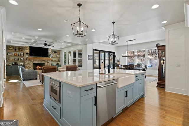 kitchen with stainless steel appliances, a fireplace, a sink, and wood finished floors