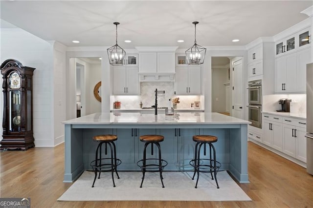 kitchen with double oven, a breakfast bar area, light countertops, and light wood-style flooring