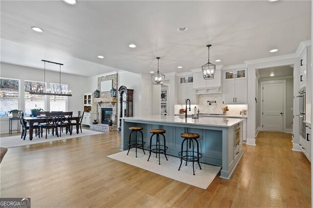 kitchen featuring light wood-style floors, white cabinetry, light countertops, and a kitchen breakfast bar