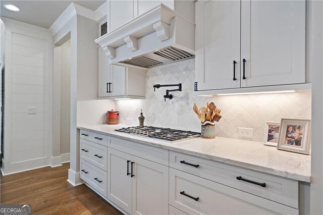 kitchen featuring light stone counters, dark wood finished floors, custom exhaust hood, stainless steel gas stovetop, and white cabinetry