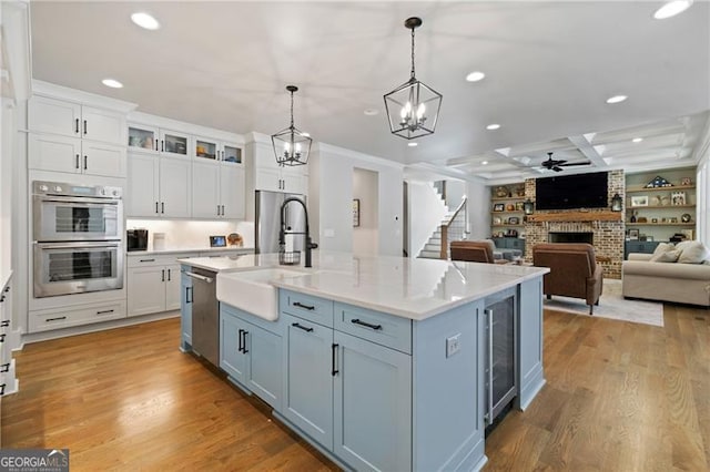 kitchen featuring stainless steel appliances, a fireplace, a sink, and white cabinetry