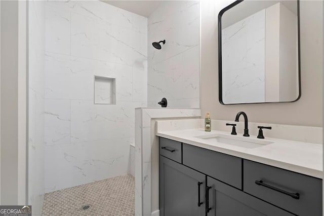 full bath featuring a tile shower and vanity