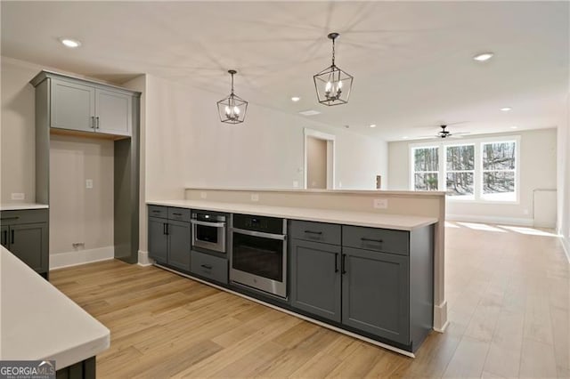 kitchen with a peninsula, light wood-style flooring, gray cabinets, and oven