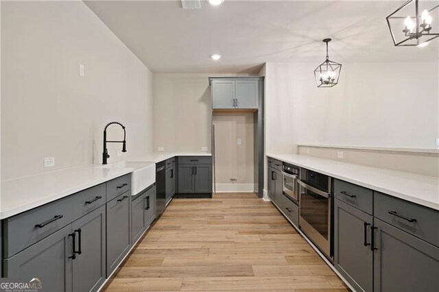 kitchen featuring a sink, light wood-style flooring, gray cabinets, and oven