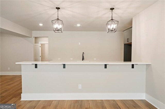 kitchen with baseboards, light countertops, an inviting chandelier, and light wood-style floors