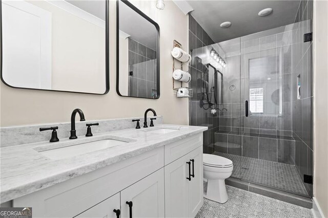 bathroom featuring a sink, a shower stall, toilet, and double vanity