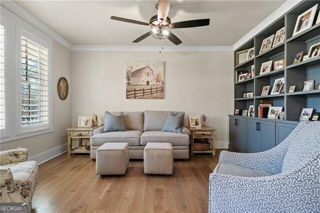 sitting room with ceiling fan, ornamental molding, and wood finished floors