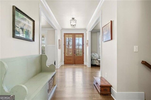 foyer entrance featuring ornamental molding, french doors, baseboards, and wood finished floors