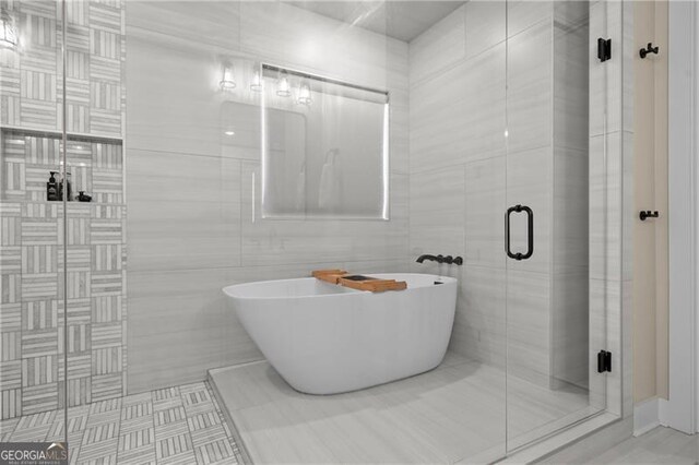 bathroom featuring a freestanding bath, a shower stall, and tile walls